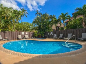 A swimming pool with lounge chairs and a wooden fence.