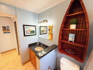A bathroom with a sink, mirror, and wooden shelf with a potted plant.