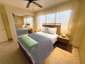 A hotel room with a bed, a nightstand, a mirror, and a ceiling fan.