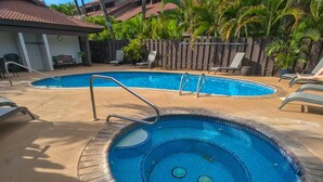 A swimming pool with a tiled edge, surrounded by lounge chairs and a wooden fence. - Where Zen Finds You Kihei Garden Condo Split AC Pool Hot Tub Near Beach (Kihei)