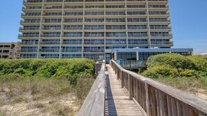 Un hotel de varios pisos con un paseo de madera que lleva a la entrada.