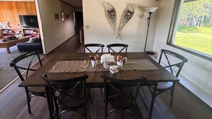 A dining area with a wooden table, four chairs, and a view of the outdoors through a large window. - Large Home with Outstanding Views & Location (Palmer)
