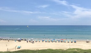 A beach with umbrellas and lounge chairs, a clear sky, and a distant boat.
