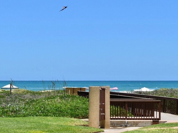 A beach view with a wooden fence, a concrete pillar, and a distant ocean.