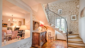A spacious living area with a stone wall, a wooden cabinet, and a staircase with a metal railing. - PROVENCE MAS IN A THOUSAND VINEYARDS VIEW ON MONT VENTOUX WITH POOL (Saint-Montan)