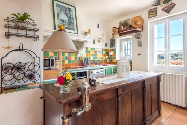 A kitchen with a wooden island, a microwave, a coffee maker, and a window with a view.