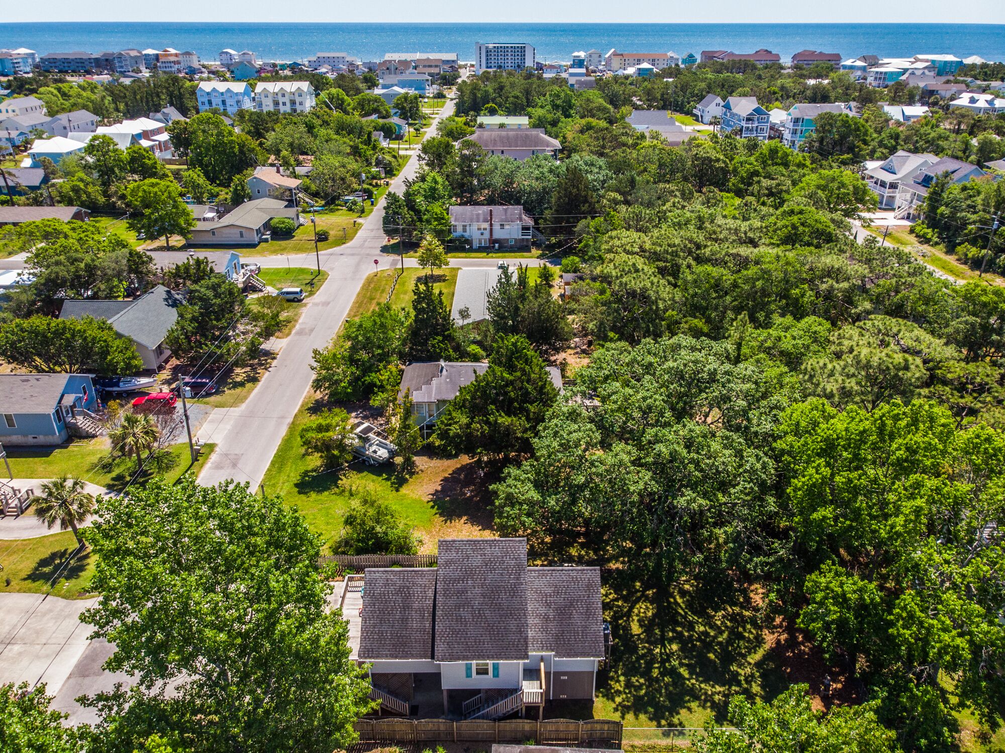 A residential area with houses, a main road, and a body of water in the background.