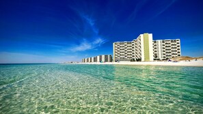 A beachfront hotel with multiple floors, clear blue water, and a sandy beach. - Cozy Summer Vacation Retreat at Hank & Grace's Hideaway @ Pinnacle Port by 30A (Panama City Beach)