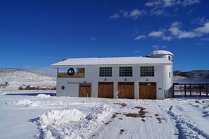 A white building with a circular roof and three wooden garage doors.