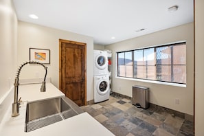 A laundry room with a washing machine, a dryer, a sink, and a window with a view.
