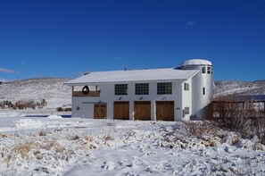 Een wit gebouw met een koepel en meerdere ramen, omgeven door een besneeuwd landschap.