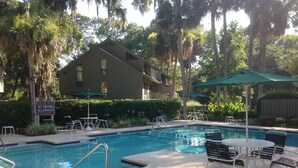 A pool area with lounge chairs and umbrellas, a sign indicating shallow water and 10 diving allowed, and a building in the background. - Great Lagoon, Tennis+pool View Townhome W/10min Walk To Golf+Beach+Harbour Town (Hilton Head Island)