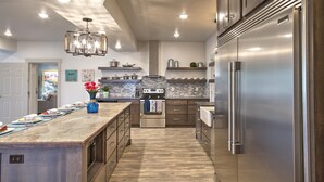 A modern kitchen with a central island, stainless steel appliances, and a chandelier.