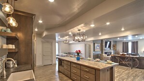 A spacious kitchen with a large island, wooden cabinetry, and pendant lighting.