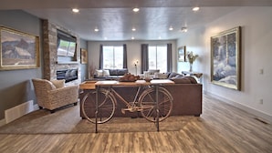 A modern living room with a stone fireplace, a large window, and a bicycle in the center.