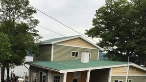 A two-story house with a green roof, a covered porch, and a garden with various plants and flowers. - Unique Space-Great View, East side Sunsets a Plus -2 Nights or More :) (Niles)