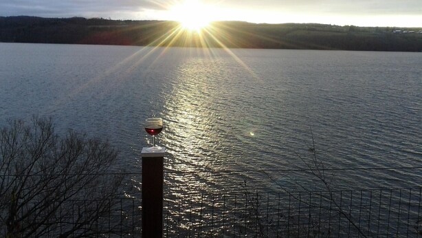 A calm lake with the sun reflecting on the water, a metal fence, and a pole with a light fixture. - Unique Space-Great View, East side Sunsets a Plus -2 Nights or More :) (Niles)