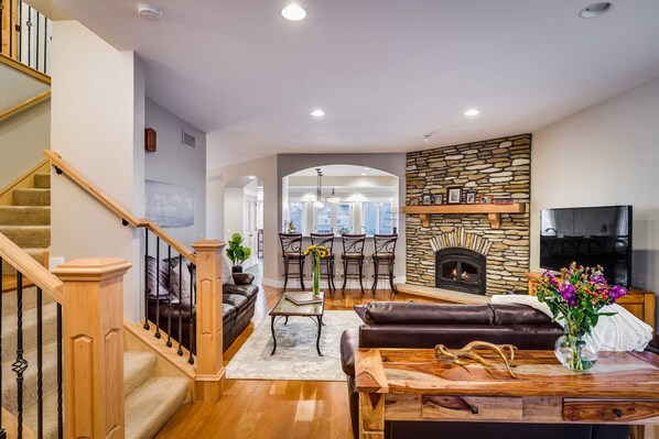 A spacious living room with a fireplace, a dining area, and a staircase. - Large Comfortable home with Flatiron views (Boulder)