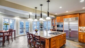 A spacious kitchen with a central island, wooden cabinets, stainless steel appliances, and large windows. - Large Comfortable home with Flatiron views (Boulder)