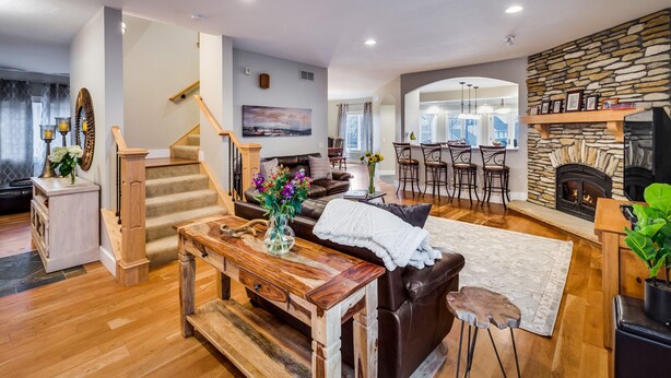 A spacious living area with a wooden staircase, a fireplace, and a dining area with bar stools. - Large Comfortable home with Flatiron views (Boulder)