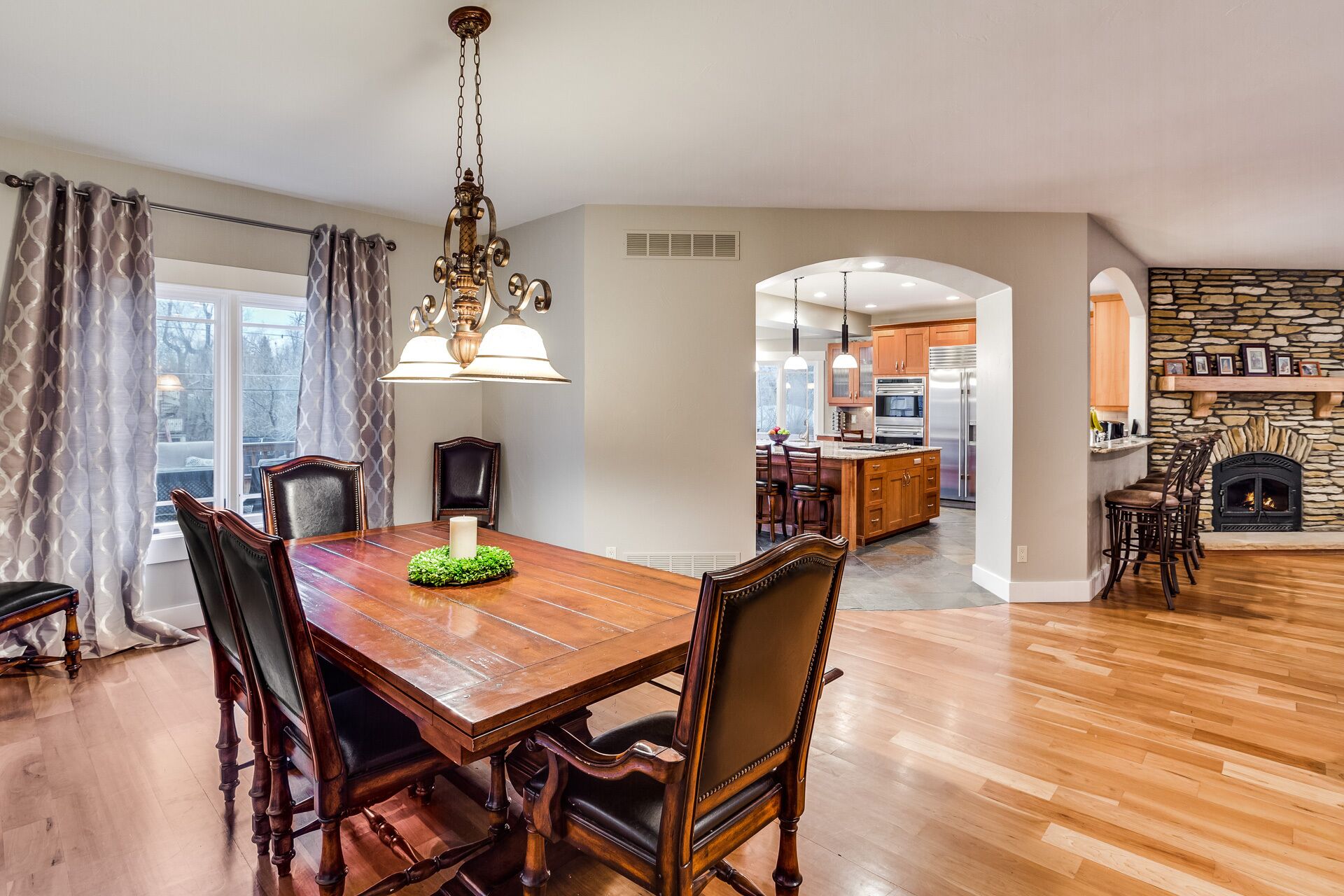 A dining area with a wooden table and chairs, a chandelier, and a view into the kitchen.