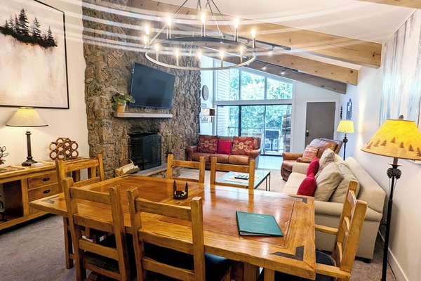 Living room with wood fireplace, dining table, and balcony w/ propane BBQ grill