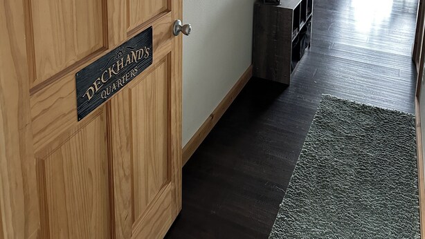 Una puerta de madera con un letrero que dice 'Bienvenido' y 'Camarotes del ayudante'.