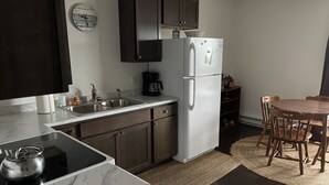 Una cocina compacta con armarios de madera oscura, un refrigerador blanco, un lavamanos y una estufa.