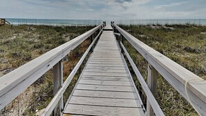 A wooden boardwalk leading to a beach with a clear sky. - Big Kahuna | Ocean Front, Pool, Elevator, Decks + Beach Access (Kure Beach)