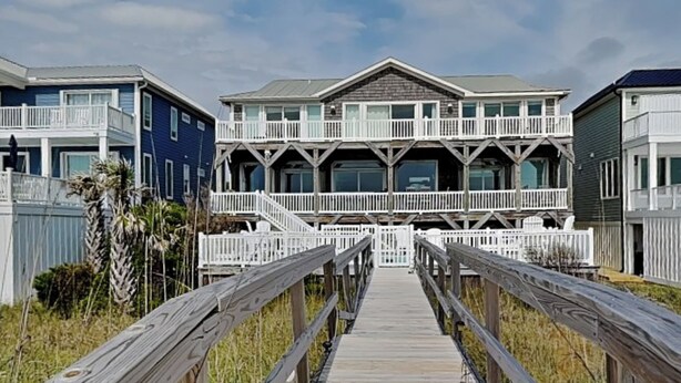 A wooden boardwalk leading to a beachfront house with multiple decks and a white fence. - Big Kahuna | Ocean Front, Pool, Elevator, Decks + Beach Access (Kure Beach)