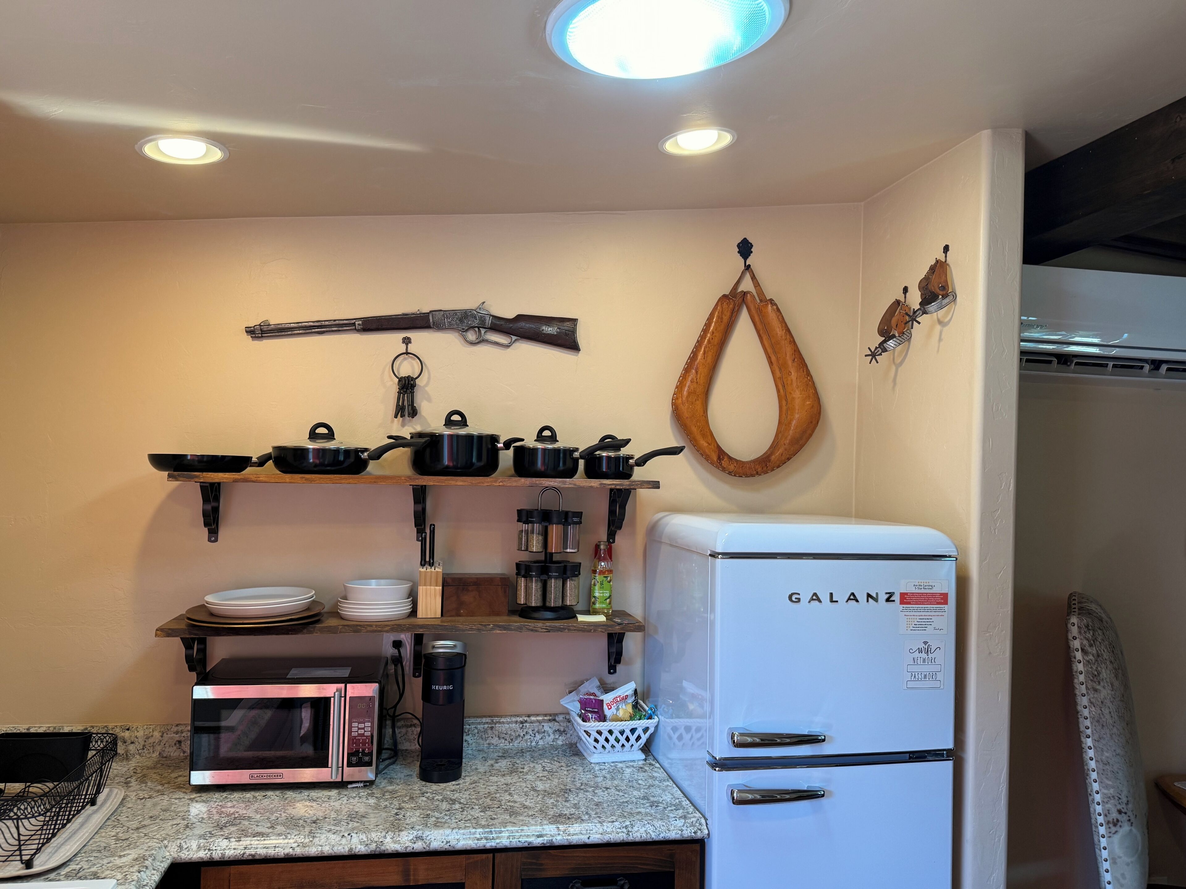 Una cocina equipada con microondas, hervidor y refrigerador.