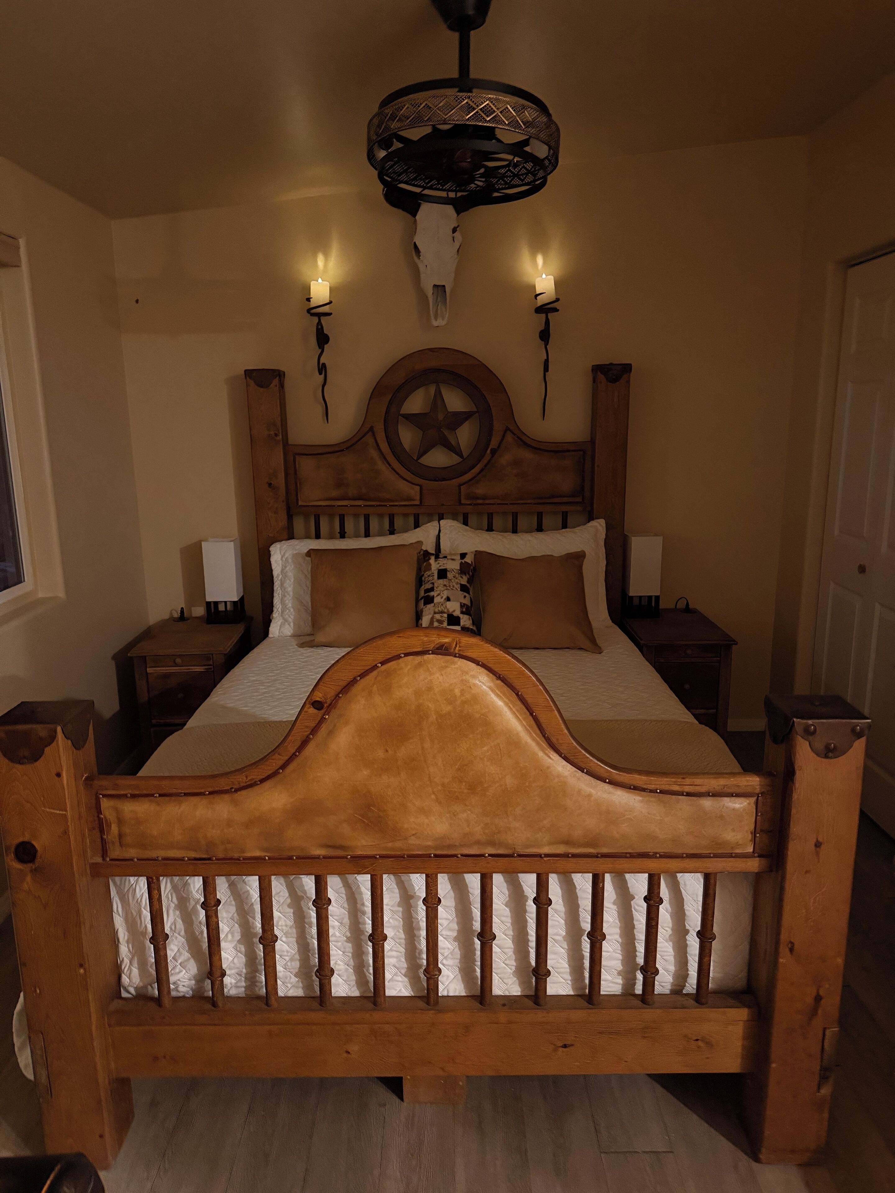 A wooden bed with a star design headboard, two bedside tables, and a hanging light fixture.