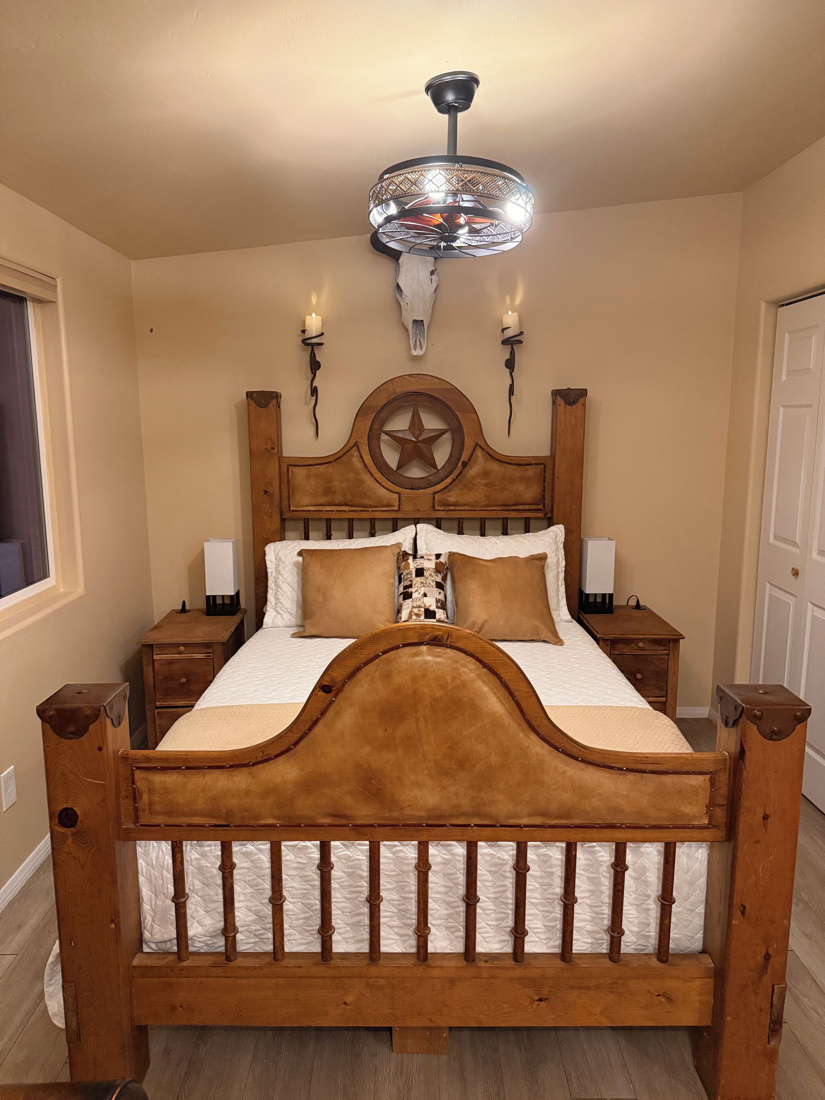 A wooden bed with a star headboard, two bedside tables, a wall-mounted star decoration, and a ceiling fan.