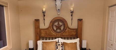 A wooden bed with a star headboard, two bedside tables, a wall-mounted star decoration, and a ceiling fan.