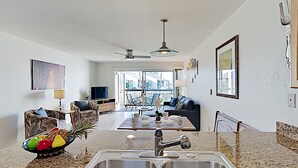 Et moderne køkken med en dobbeltvask, et spiseområde med bord og stole, en sofa og et fjernsyn.