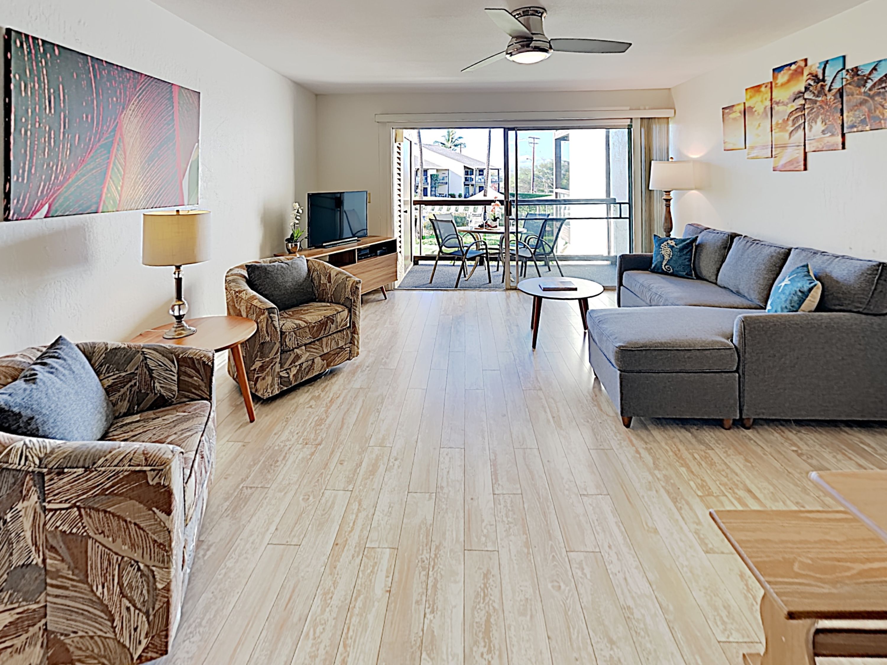 A spacious living room with a sofa, armchairs, a coffee table, and a TV.
