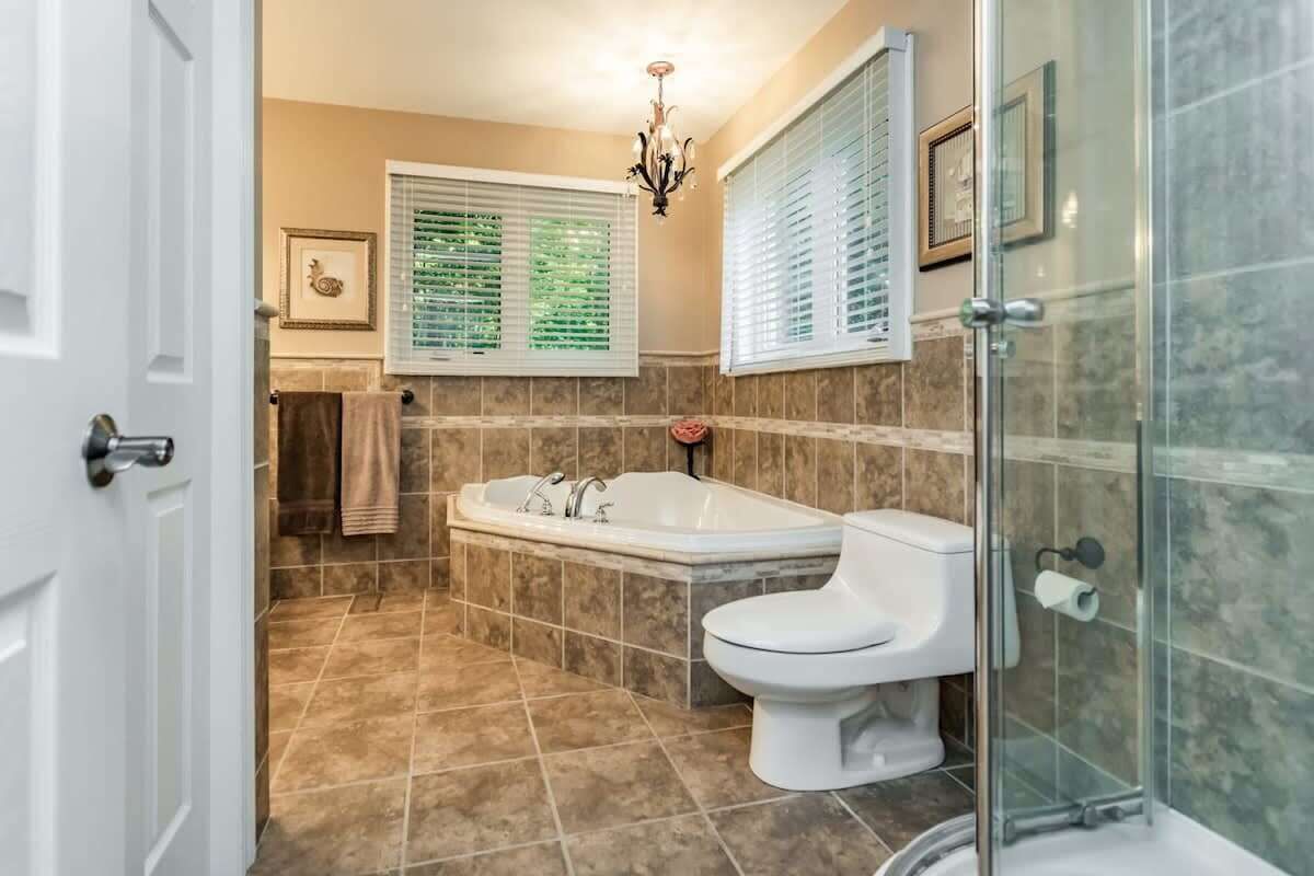 A bathroom with a bathtub, toilet, and glass shower enclosure.