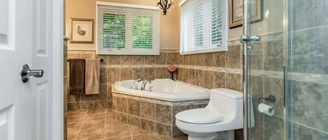 A bathroom with a bathtub, toilet, and glass shower enclosure.
