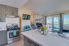 A kitchen with a stove, oven, and a dining area with a table set for two.