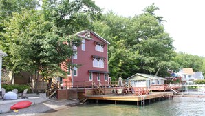 A waterfront property with a dock, a red building, and outdoor seating. - Modern Lakefront home (Hammondsport)