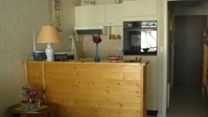 A compact kitchen with basic amenities, a wooden counter, and a small table with a vase. - Well-located apartment, terrace with sea view. 50 m from the beach. For 2-4 pers    (Les Sables-D'olonne)