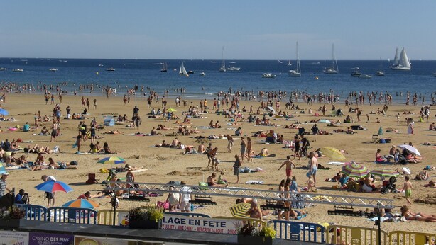 A crowded beach with people sunbathing and swimming, boats in the water, and a sign advertising a casino. - Well-located apartment, terrace with sea view. 50 m from the beach. For 2-4 pers    (Les Sables-D'olonne)
