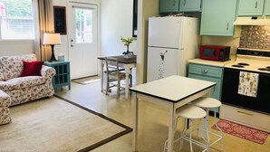 A compact kitchen with teal cabinets, a white refrigerator, a red microwave, and a vintage stove. - Piper's Flat, Cozy, Comfy & Sparkling Clean (Aiken)