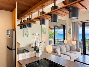 A modern kitchen with a built-in stove, a dining area with a table and chairs, and a living room with a sofa.