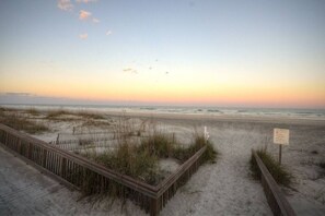 A beach with a wooden boardwalk, sand dunes, and a signpost. - Ocean Reef 203 (St. Augustine)