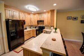 A kitchen with wooden cabinets, a black refrigerator, a stove, and a sink.