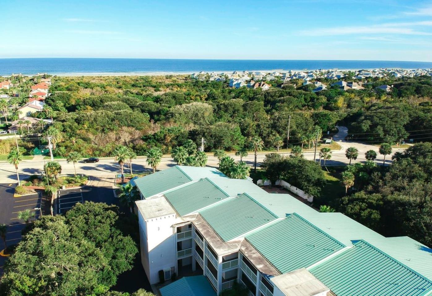 A residential area with multiple buildings, a parking lot, and a view of the ocean.