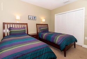 A bedroom with two single beds, a closet, and two wall-mounted lamps.