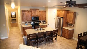 Una cocina amplia con armarios de madera, un refrigerador de acero inoxidable, un microondas y una isla grande con sillas.