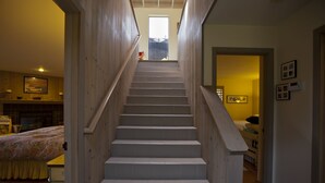 Una escalera conduce a un dormitorio con una cama y una ventana.